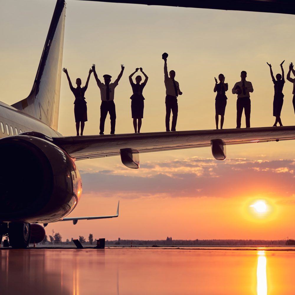happy-friendly-solid-team-of-pilots-and-stewardesses-isolated-on-sunset-background.jpg